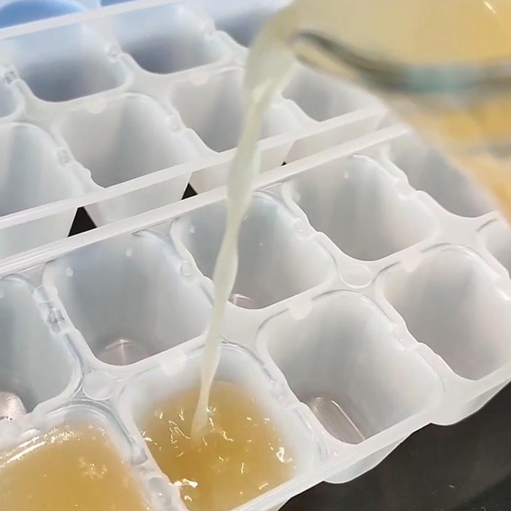 Jarro a despejar caldo de ossos liquido em cuvetes de gelo