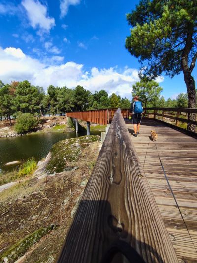 Homem a percorrer os passadiços do Távora, vila da ponte, Portugal, um pequeno cão idoso caminha atrás dele.