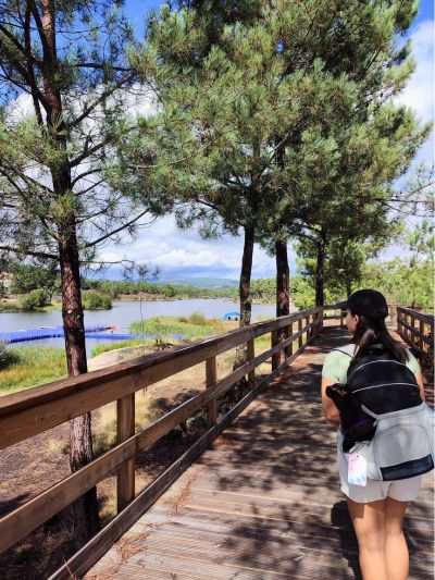 Mulher a percorrer os passadiços do Távora, vila da ponte, Portugal, com um gato paraplégico numa mochila para transporte de caes às costas